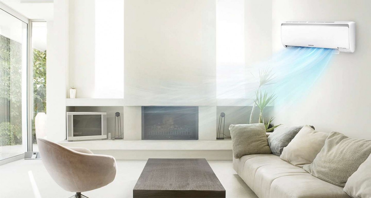 Imagem da sala de uma casa com sofá, poltrona, televisor, tapete, lareira. Ar-Condicionado Digital Inverter na parede do lado direito da imagem, dele saem raios azuis para representar o seu resfriamento rápido de ambiente.